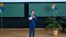 Mann hält Vortrag auf einer Bühne im Hörsaal