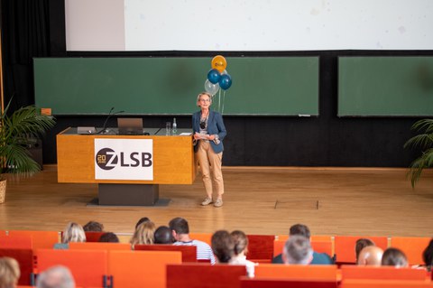 Frau hält Vortrag im auf der Bühne im Hörsaal.