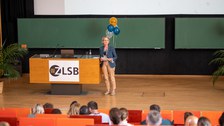 Frau hält Vortrag im auf der Bühne im Hörsaal.