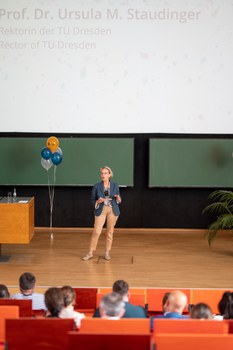 Frau hält Vortrag im auf der Bühne im Hörsaal.