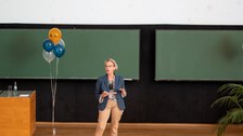 Frau hält Vortrag im auf der Bühne im Hörsaal.