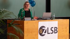 Frau hält Vortrag und steht an einem Pult.