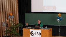 Frau hält Vortrag und steht an einem Pult.