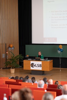 Frau hält Vortrag und steht an einem Pult.