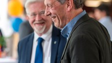 Zwei Männer unterhalten sich und lächeln dabei.