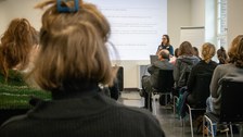 Foto zeigt einen Saal mit einer Frau, die einen Vortrag hält.