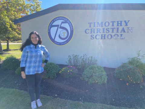 Frau steht neben einem Schulgebäude mit dem Namen "Timothy Christian School"