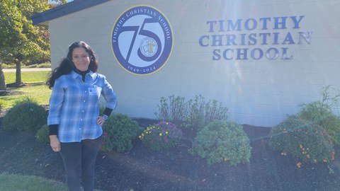 Frau steht neben einem Schulgebäude mit dem Namen "Timothy Christian School"