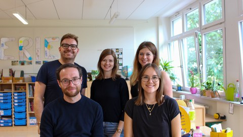 Gruppenbild mit drei Frauen und zwei Männern in einem Klassenzimmer