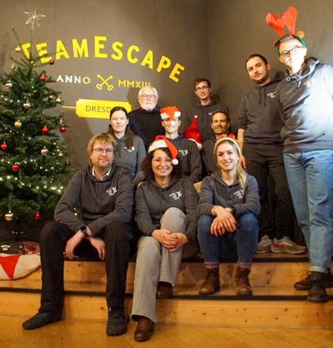 Gruppenbild mit ca. 10 Teammitglieder:innen um einen Weihnachtsbaum