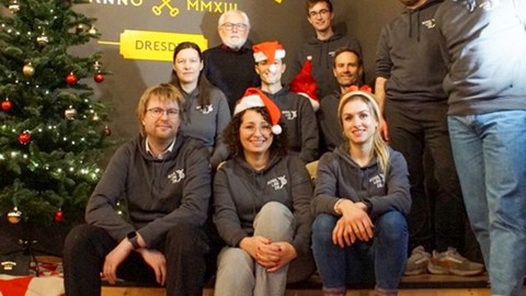 Gruppenbild mit ca. 10 Teammitglieder:innen um einen Weihnachtsbaum