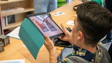 Ein junger Mann hält ein Tablet in der Hand und nutzt gerade eine Augmented Reality Application.