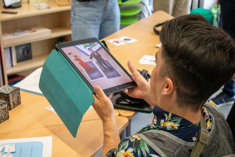 Ein junger Mann hält ein Tablet in der Hand und nutzt gerade eine Augmented Reality Application.