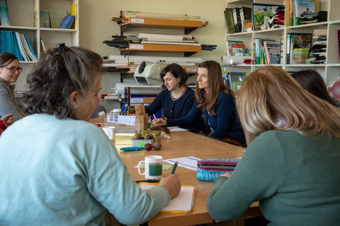 Zu sehen sind Frauen, die an einem Tisch sitzen, zuhören und mitschreiben während eines Workshops.