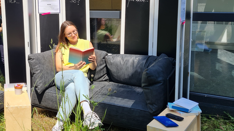 Frau sitzt auf Sofa und liest Buch