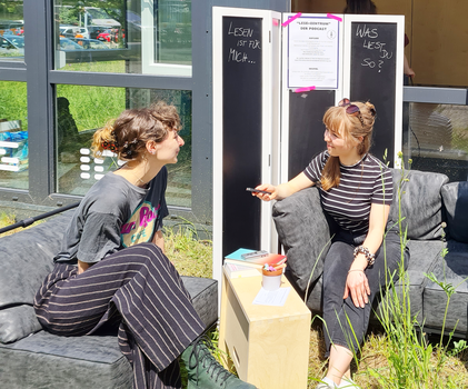 Zwei Frauen sitzen auf Sofa und unterhalten sich