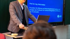 Mann hält Vortrag und steht dabei an einem Pult