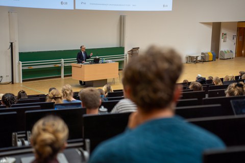 Mann hält Vortrag in einem Hörsaal an einem Rednerpult.