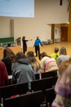 Mann macht bewegte Pause in einem Hörsaal mit Dehnübungen im Stehen