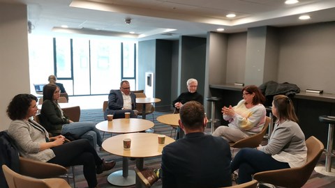 Foto: Sindy Riebeck, Martin Neumärker, Pamela O‘ Brien, Natasha Kiely, Conor Galvin, Axel Gehrmann, Tina Czaja (v.l.n.r. im Uhrzeigersinn) sitzen im Kreis um drei Tische und sind im Gespräch.