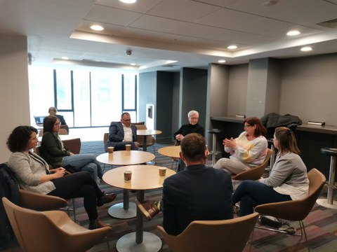 Foto: Sindy Riebeck, Martin Neumärker, Pamela O‘ Brien, Natasha Kiely, Conor Galvin, Axel Gehrmann, Tina Czaja (v.l.n.r. im Uhrzeigersinn) sitzen im Kreis um drei Tische und sind im Gespräch.