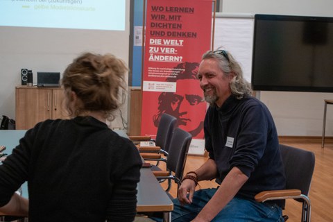 Mann und Frau unterhalten sich an einem Tisch.