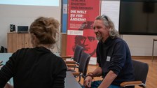 Mann und Frau unterhalten sich an einem Tisch.