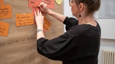 Frau pinnt Zettel an eine Pinnwand.