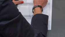 Nahaufnahme einer Hand, die etwas auf einem Blatt Papier schreibt.