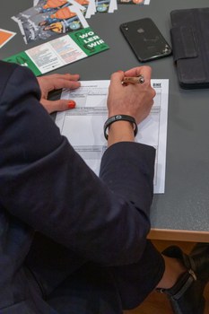 Nahaufnahme einer Hand, die etwas auf einem Blatt Papier schreibt.