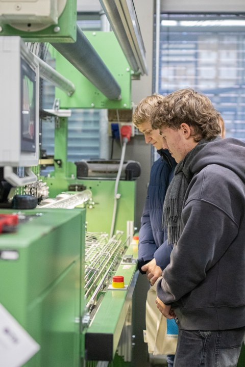 Zwei Jugendliche, die an einer großen Maschine arbeiten