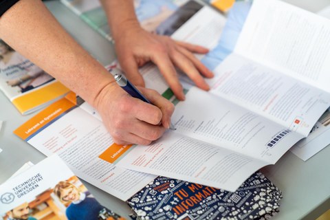 Eine Hand zeigt etwas auf einer Infobrochüre zum Lehramtsstudium