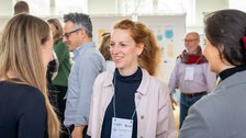 Eine Frau spricht mit anderen Konferenzteilnehmern.