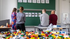4 Personen schauen sich Ausdrucke auf einer Tafel an.
