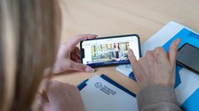 Auf einem Handy ist ein Frau zu sehen und eine App. 