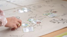 Eine Hand legt einen kleinen Zettel auf eine Weltkarte.