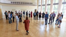 Das Foto zeigt ca. 25 Personen, die in einem Festsaal in kleineren Grüppchen stehen.