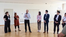 Das Foto zeigt sechs Personen, die nebeneinander stehen. Eine Person hält ein Mikrofon in der Hand.