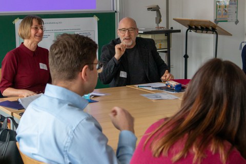 Foto: Mehrere Personen sitzen um einen Tisch und unterhalten sich.