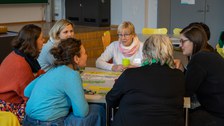 Foto: Mehrere Personen sitzen um einen Tisch und unterhalten sich.