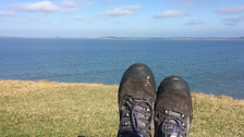 Wanderschuhe mit dem Meer im Hintergrund