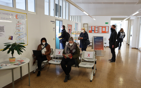 Das Foto zeigt fünf wartende Personen, dir vor dem Frontdesk des Studienbüros Lehramt stehen oder sitzen.