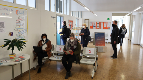 Das Foto zeigt fünf wartende Personen, dir vor dem Frontdesk des Studienbüros Lehramt stehen oder sitzen.