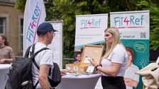 Eine Frau und ein Mann reden an einem Informationsstand miteinander