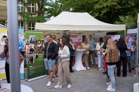 Ein Innenhof eines Unigebäudes mit vielen Informationsständen in Zelten; es herrscht buntes Treiben.