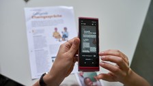 Ein spezielles Gerät, was einem Smartphone ähnelt, welches auf ein Blatt Papier mit Text gerichtet ist. 