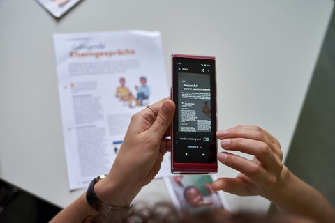 Ein spezielles Gerät, was einem Smartphone ähnelt, welches auf ein Blatt Papier mit Text gerichtet ist. 