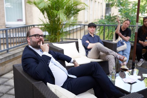 Ein Mann spricht mit mehreren jungen Leuten auf einer Sofa Lounge.