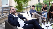 Ein Mann spricht mit mehreren jungen Leuten auf einer Sofa Lounge.