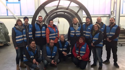 Foto: Gruppenbild von Personen in Warnwesten in einer Werkhalle